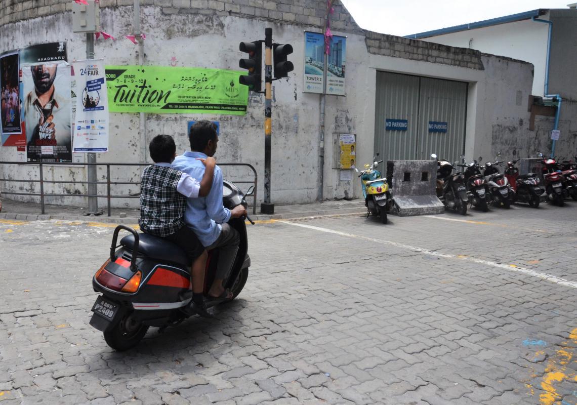 A father and his child ride on a motorbike without helmets in Malé. UNICEF Maldives. 2019. Miolene